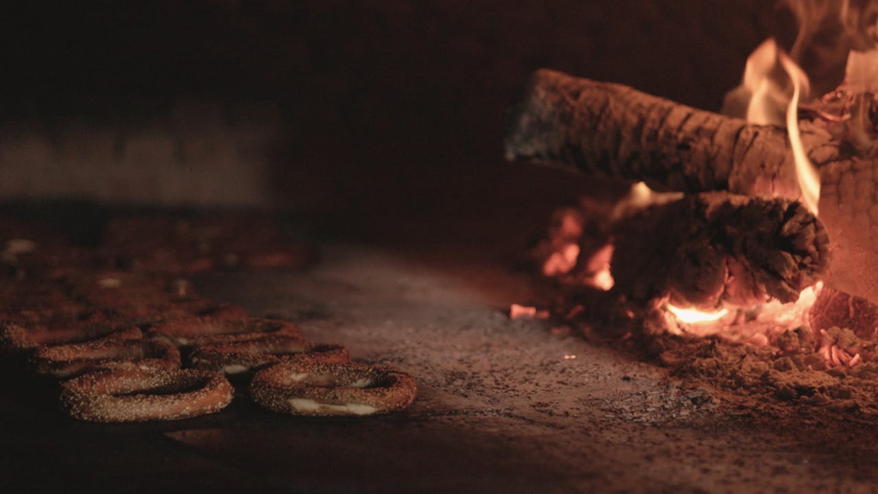portfolio-03 Rustic bagels baking in a traditional wood-fired oven with glowing flames.